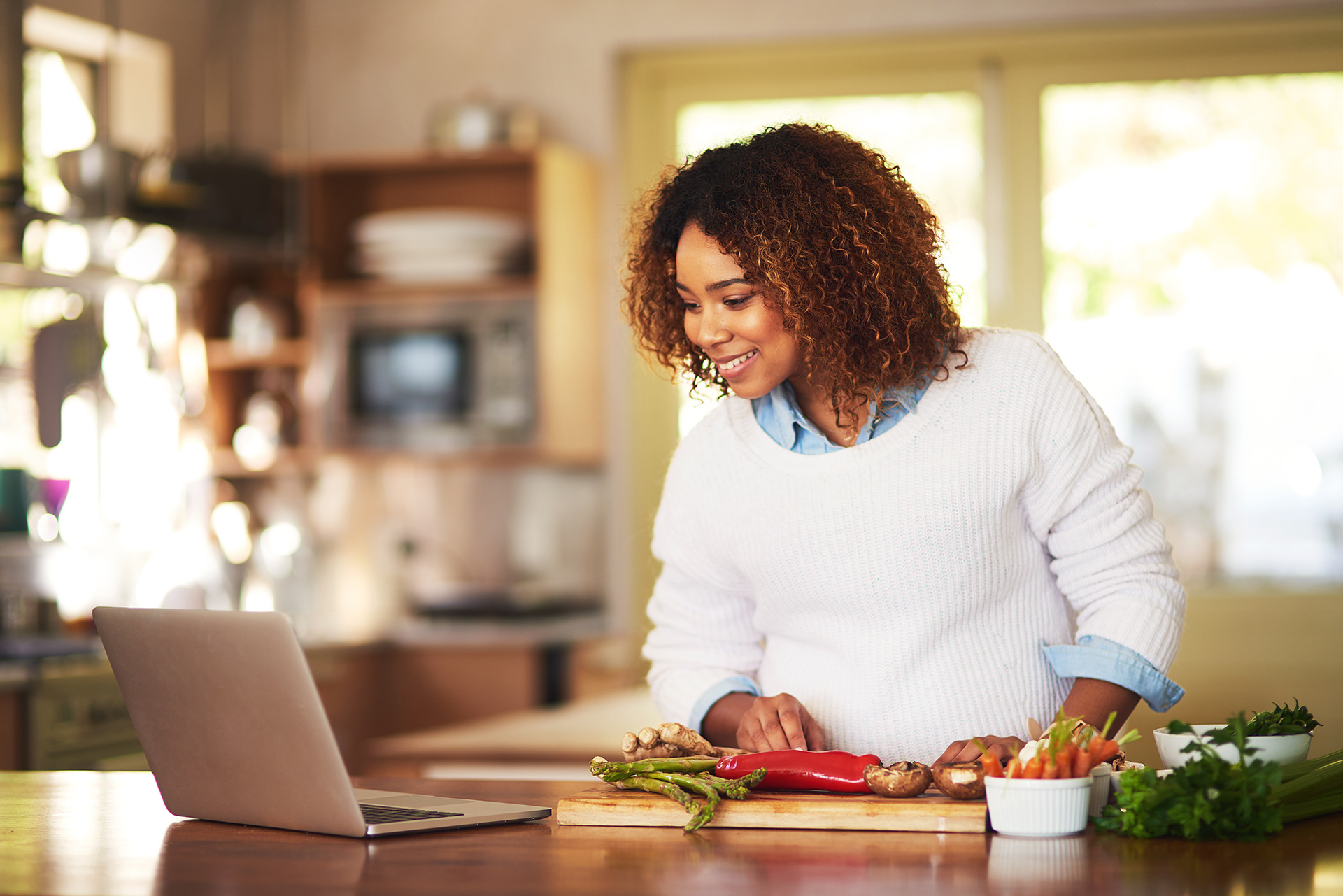 Meal planning is a breeze with modern technology. Shot of a young woman using a laptop while preparing a healthy meal at home